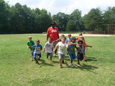 Cute little children running along with the coach at YMCA of Greater Charlotte
