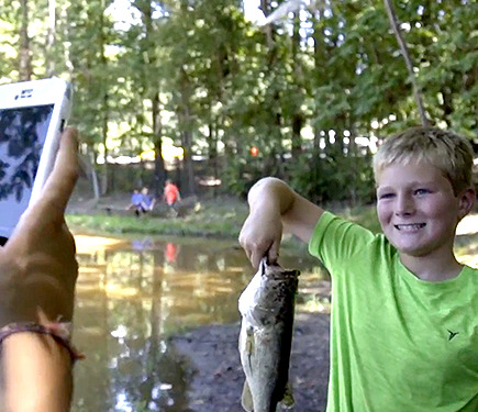 A boy with a fish in his hand at YMCA of Greater Charlotte adventure day camp