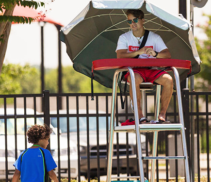 A lifeguard watches a kid walking by