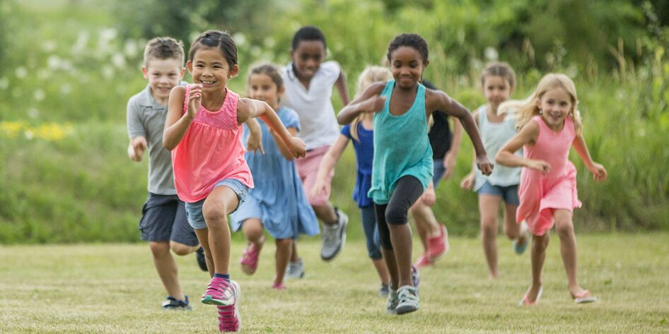 group of diverse children racing in an open field