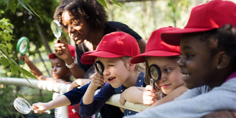 a group of diverse children using magnifying glasses to explore the world