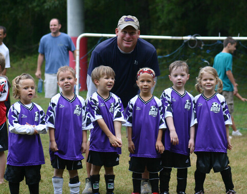 Little kids with their coach having fun at YMCA recreational soccer