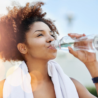 Cropped shot of a young woman enjoying a bottle of water while out for a run